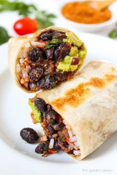 a burrito with black beans and guacamole is on a white plate