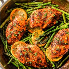 chicken, asparagus and oranges in a skillet with lemon wedges