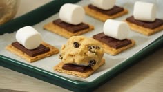 marshmallows and chocolate chip cookies are arranged on a cookie sheet with graham crackers