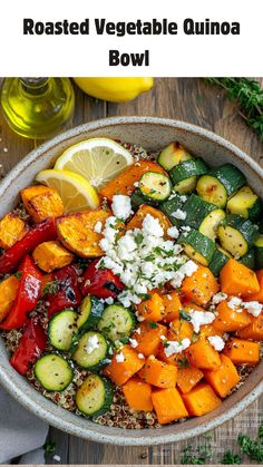 roasted vegetable quinoa bowl with feta cheese and lemon wedges on the side