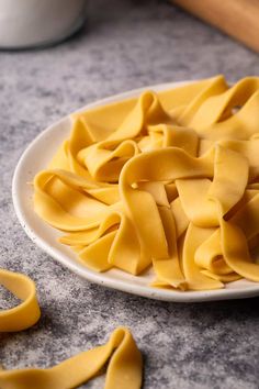 a white plate filled with uncooked pasta sitting on top of a counter next to scissors