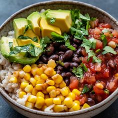 a bowl filled with black beans, corn and avocado on top of rice