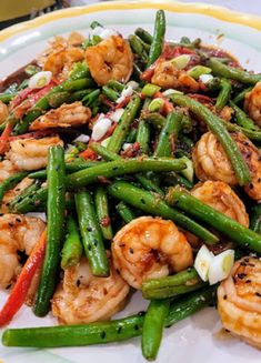 a white plate topped with green beans and shrimp