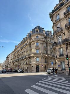 a large building with many windows and balconies on the top floor, next to a crosswalk