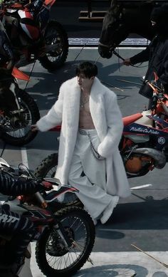 a man in white clothes standing next to a motorcycle