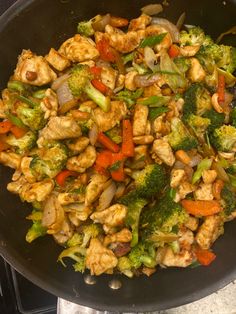 a pan filled with chicken and vegetables on top of a stove