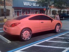 an orange car parked in front of a walmart