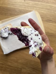 a hand holding a piece of food on top of a white plate