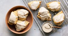 some food is sitting on a wire rack and next to a bowl with icing