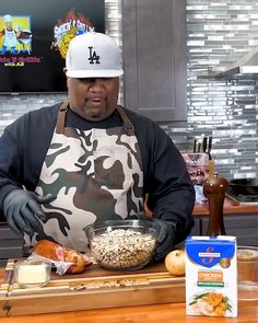 a man in an apron and hat preparing food on a counter with other items around him