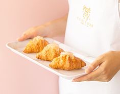 a person holding a tray with croissants on it