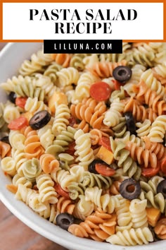 pasta salad recipe in a white bowl with olives, tomatoes, and other ingredients