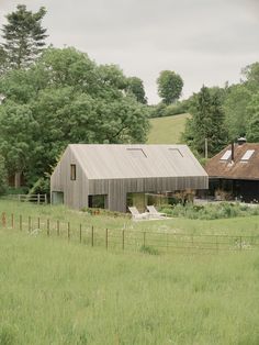 an old barn sits in the middle of a field