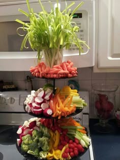 three tiered trays filled with vegetables on top of a kitchen stovetop next to a microwave