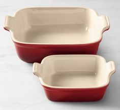 two red casserole dishes sitting on top of a white countertop next to each other