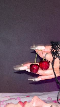 A girl with long and sharp nails holding really ripe cherries 🍒