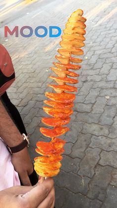 a man is holding up some food on a stick