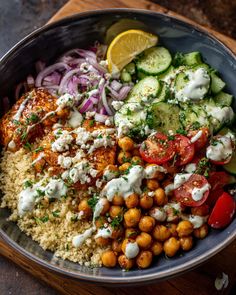 a bowl filled with rice, cucumber, tomatoes and chickpea salad