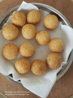 small round breaded pastries in a metal bowl on a wooden table with white napkins