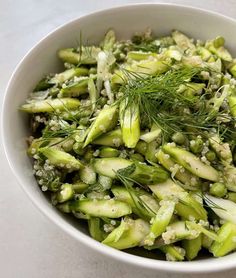 a white bowl filled with green vegetables on top of a table
