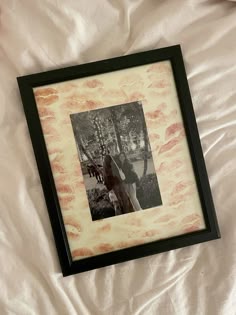 a black and white photo in a frame on a bed