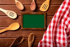 wooden spoons and utensils on a table with a green chalkboard in the middle