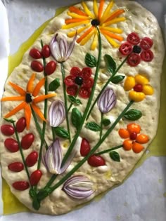 a pizza decorated with colorful flowers and vegetables