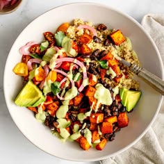 a white bowl filled with vegetables and rice next to a cup of coffee on a table