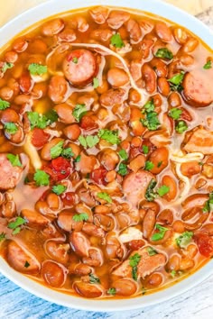 a bowl of beans and sausage soup with parsley garnish on the side