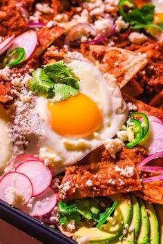 an egg is sitting on top of some meat and veggies in a pan