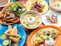 several plates of food are arranged on a colorful tablecloth, including french fries and salads