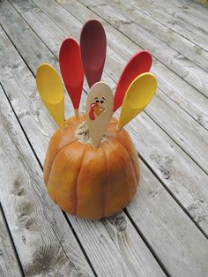 a pumpkin shaped like a turkey sitting on top of a wooden deck