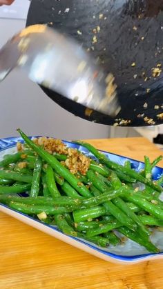 someone is cooking green beans on a blue and white plate