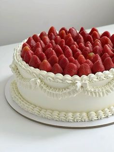 a white cake topped with fresh strawberries on top of a table