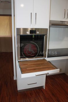 a kitchen with wooden flooring and white cabinetry, including a stainless steel oven