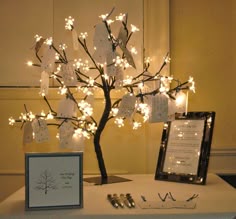a table with a tree decorated with cards and lights on it, next to a framed photo