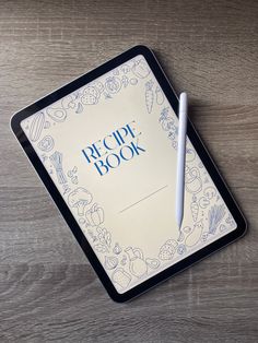 a recipe book with a pen sitting on top of it next to a tablet computer