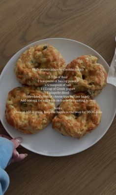 three biscuits on a white plate sitting on a wooden table