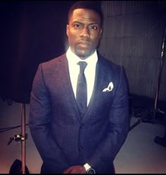 a man in a suit and tie standing next to a camera with his hands on his hips