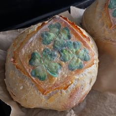 two loaves of bread with shamrocks painted on them, sitting on wax paper
