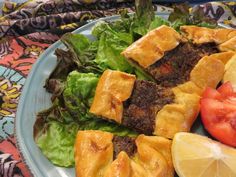 a blue plate topped with meat and veggies next to a slice of lemon