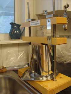 a large metal pot sitting on top of a wooden stand next to a kitchen sink
