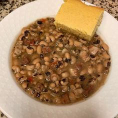 a white bowl filled with beans and a piece of bread