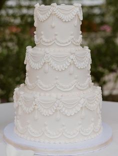 a three tiered white wedding cake sitting on top of a table