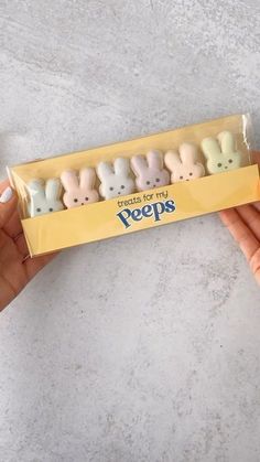 a person holding a box of pees with four small bunnies in the middle