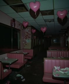 the interior of a diner with pink booths and heart shaped balloons hanging from the ceiling
