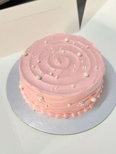 a pink frosted cake sitting on top of a white table