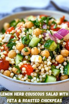 a salad with chickpeas, cucumbers and tomatoes in a white bowl