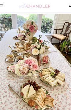 a table topped with plates filled with sandwiches and desserts next to a vase full of flowers