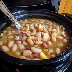 a black crock pot filled with beans and potatoes